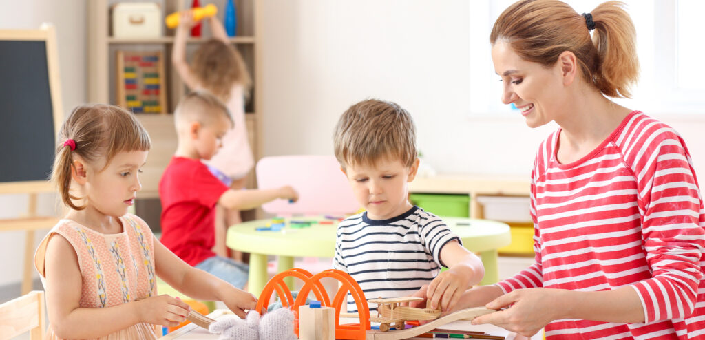 Nursery teacher with cute little children in kindergarten